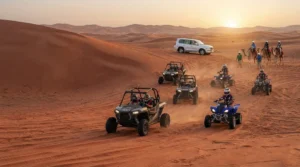 Quad bikes and dune buggies driving across desert dunes at sunset near camels and a white SUV.