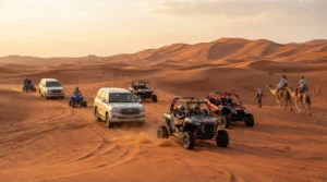 Dune buggies, quad bikes, SUVs, and camels traverse golden desert sand dunes under warm sunlight.