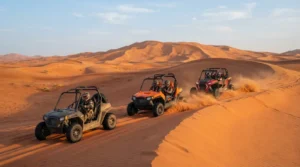 Helmeted drivers in three roll-cage dune buggies cross red sand dunes near Dubai in warm late afternoon light